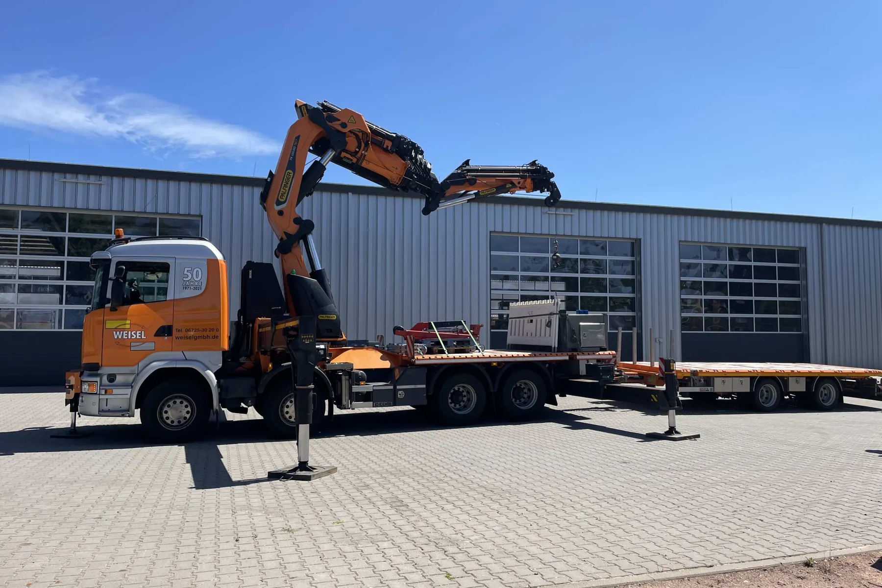 Lkw-Ladekran hebt eine Last an einer Hallenwand